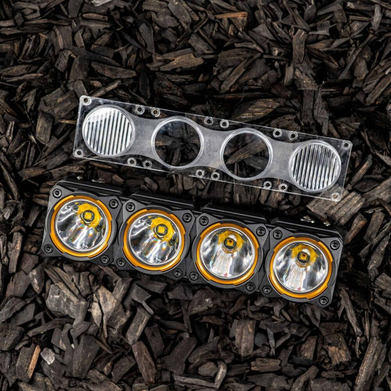 KC HiLiTES FLEX ERA LED Light Bar Replacement Lens on a vehicle: clear FLEX ERA combo lens resting above a four-pod KC light bar on dark wood chips