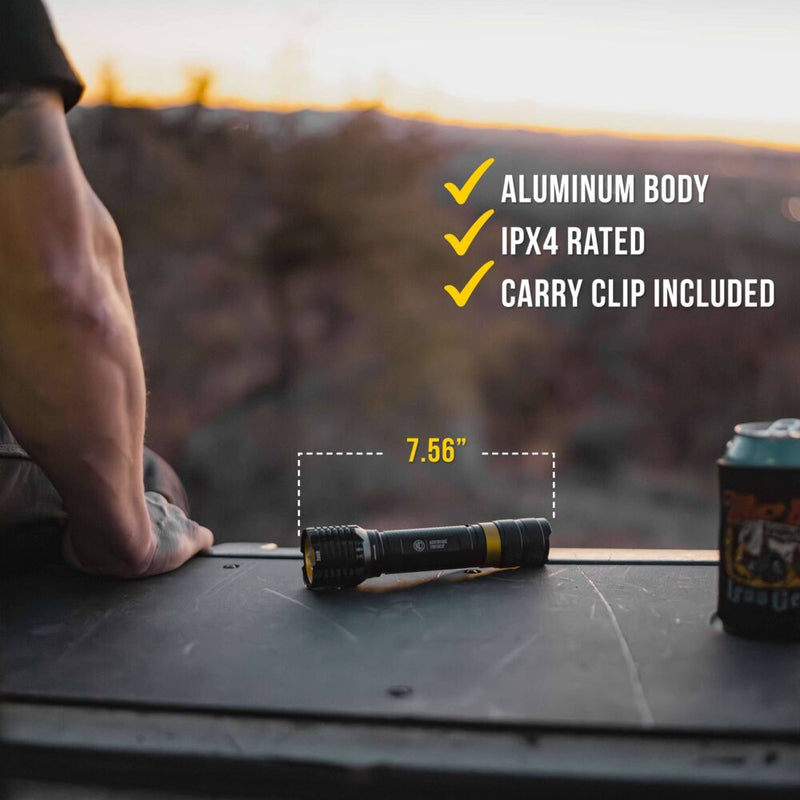 KC HiLiTES FLX 3K Rechargeable Flashlight on a vehicle: flashlight lying on a dark tailgate at sunset next to a man's forearm and a drink can in a koozie