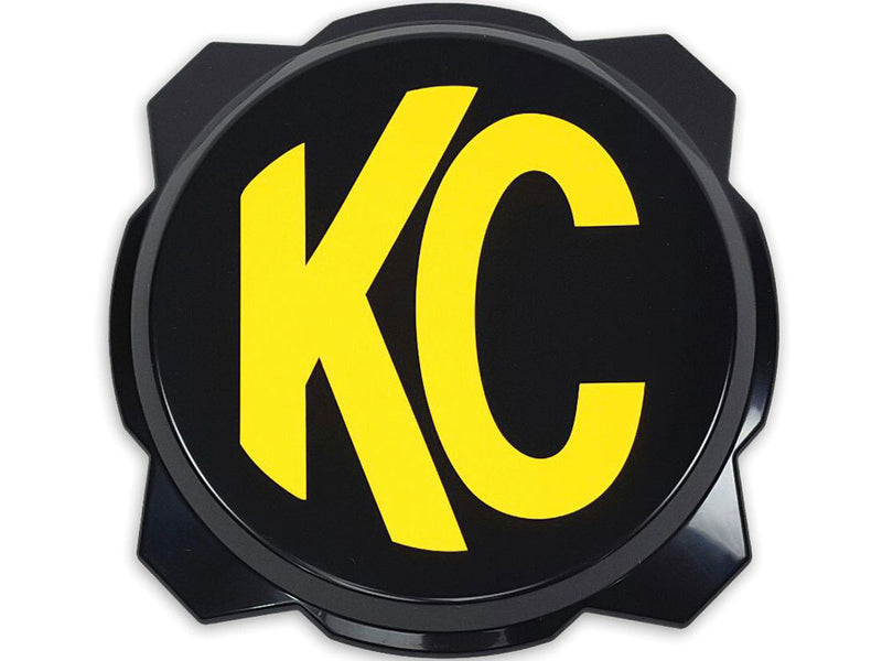 KC HiLiTES Gravity Titan & Pro6 6" Light Cover & Shield on a studio background: black 6" Pro6 light cover with a yellow KC logo, front view