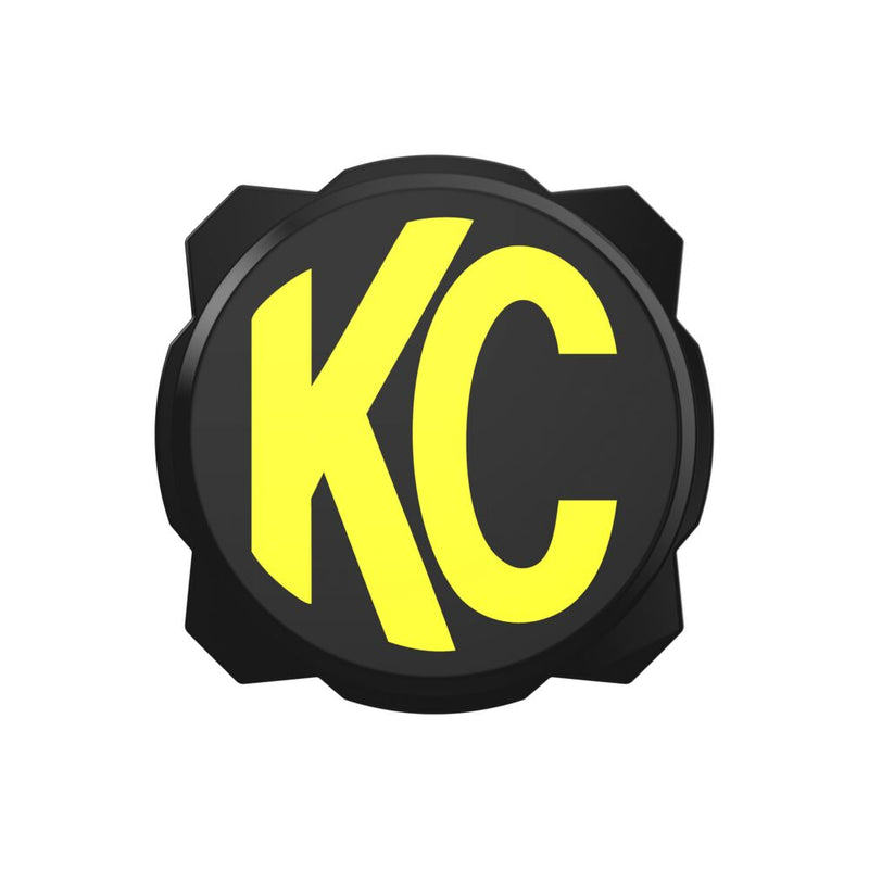 KC HiLiTES Gravity Titan & Pro6 6" Light Cover & Shield on a studio background: black 6" Pro6 light cover with a yellow KC logo, front view