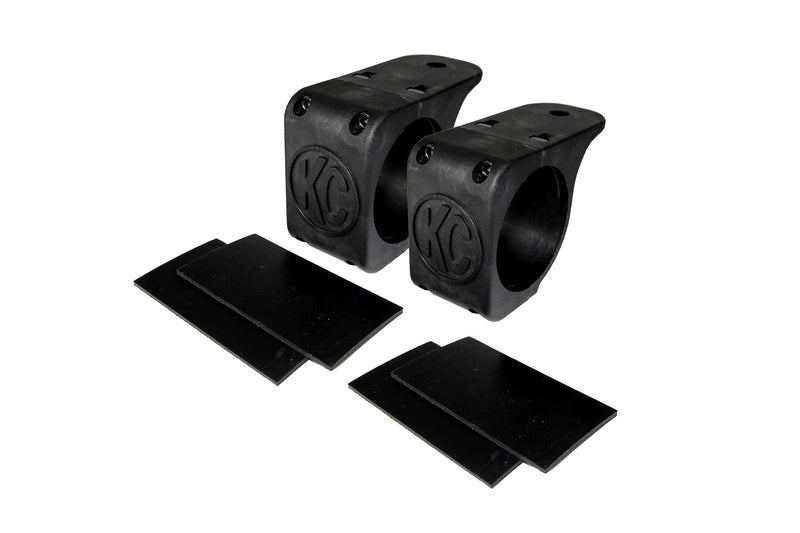 KC HiLiTES Tube Clamp Light Mount on a studio background: pair of black KC tube clamp light mounts, each with two black rubber adjustment shims on a white background