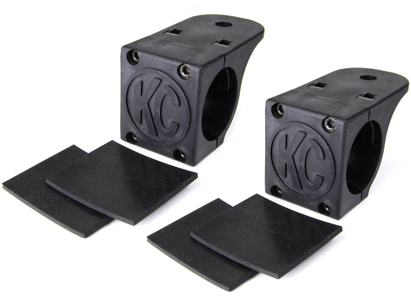 KC HiLiTES Tube Clamp Light Mount on a studio background: pair of black KC tube clamp light mounts, each with two black rubber adjustment shims on a white background