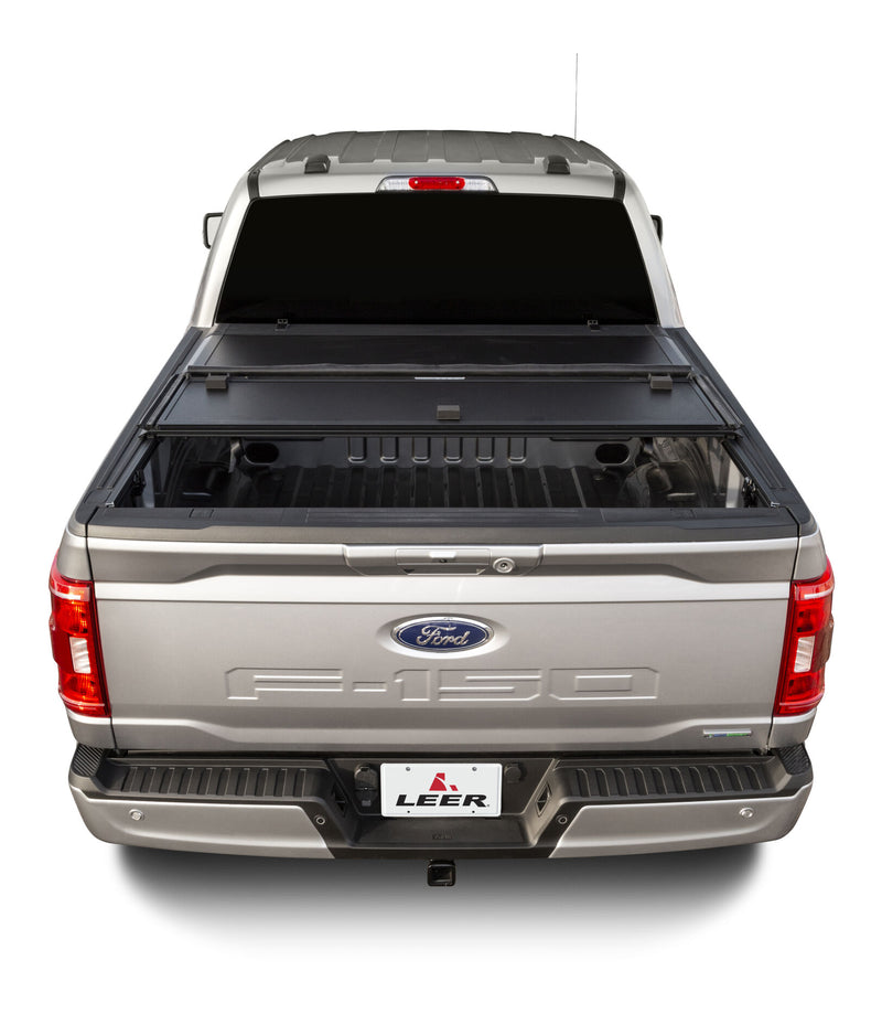 LEER HF350M hard folding tonneau cover on a pickup bed: rear view of a hard tri-fold cover partly open, rear panel folded forward on a silver pickup