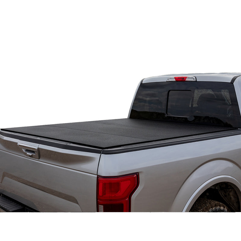 LOMAX Hard Tri-Fold tonneau cover: silver pickup on white background, rear 3/4 view, hard tri-fold cover closed with smooth textured matte-black panels