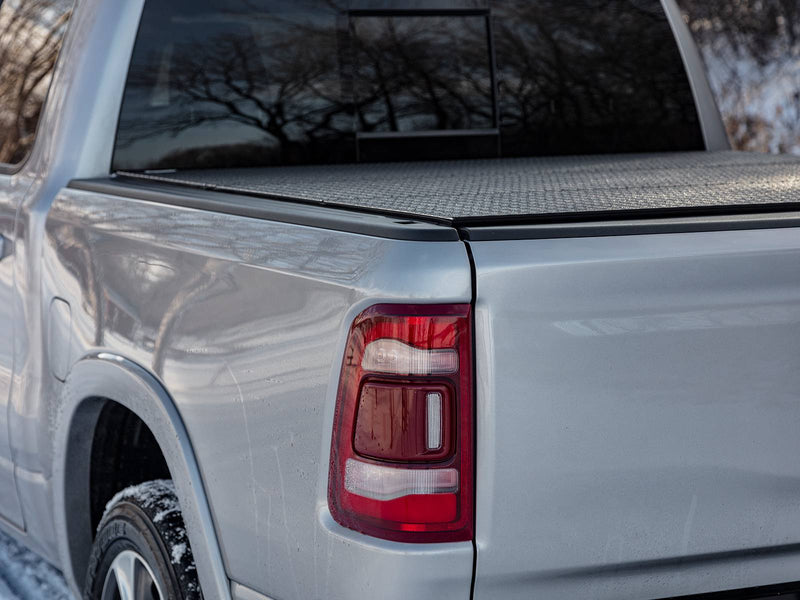 Close rear-quarter view of a silver pickup with the diamond-pattern cover closed flush with the bed rails
