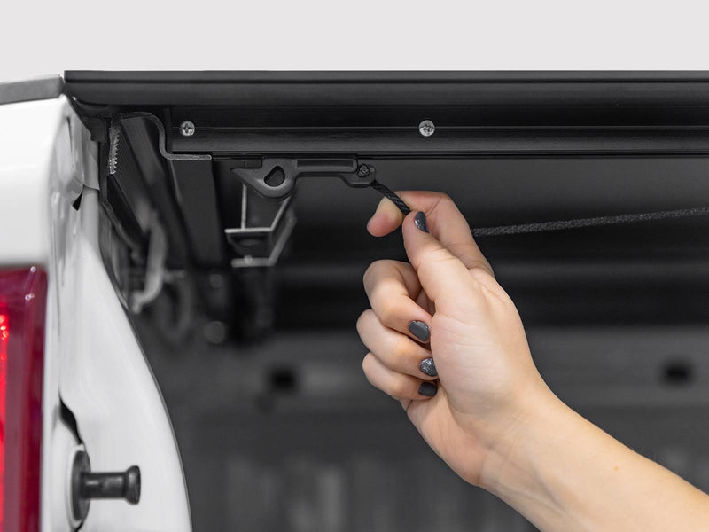 Hand pulling the cable latch release under the cover rail