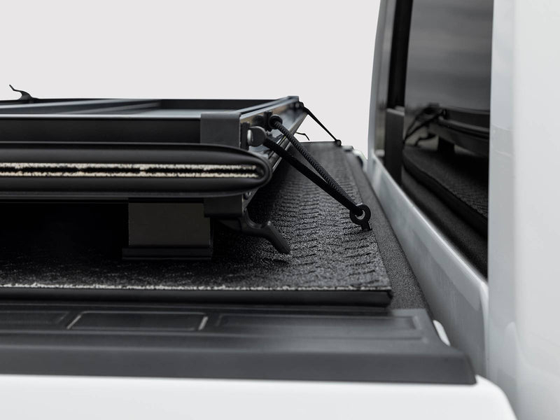 Folded cover stack held by the storage clip/strap at the front of the bed
