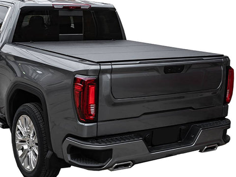 Grey pickup on white, low-profile black hard tri-fold tonneau cover closed, rear three-quarter view