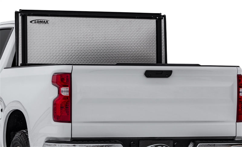 LOMAX STANCE tonneau cover: white pickup studio crop, STANCE panels vertical showing embossed-aluminum underside with 'LOMAX STANCE HARD COVER' decal