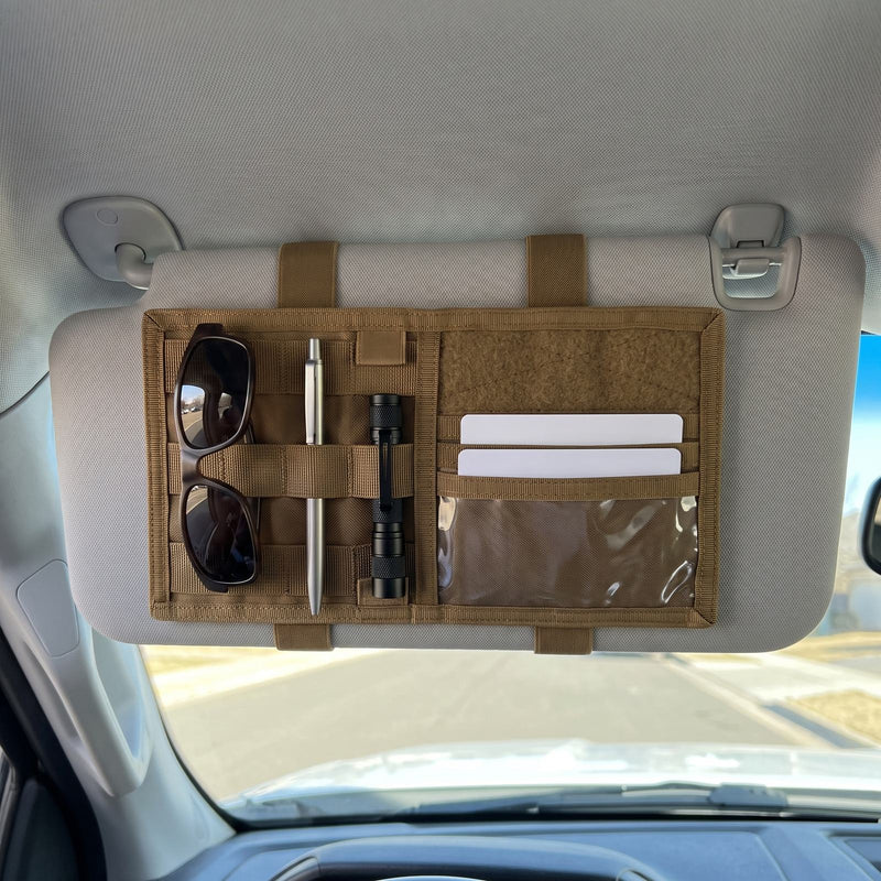 MOLLE sun visor organizer strapped to the driver side sun visor of a pickup truck, holding sunglasses, a pen, a small flashlight and two cards