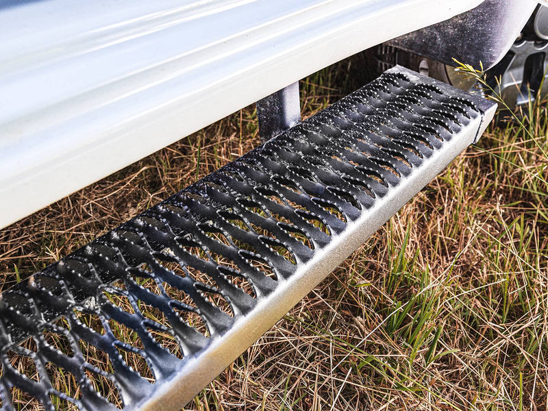 Close-up of a dew-wet Growler Fleet grip-plate step under a white truck