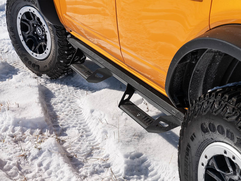 N-Fab Predator Pro nerf steps in textured black, installed along the rocker in snow, on a Ford Bronco 4-door