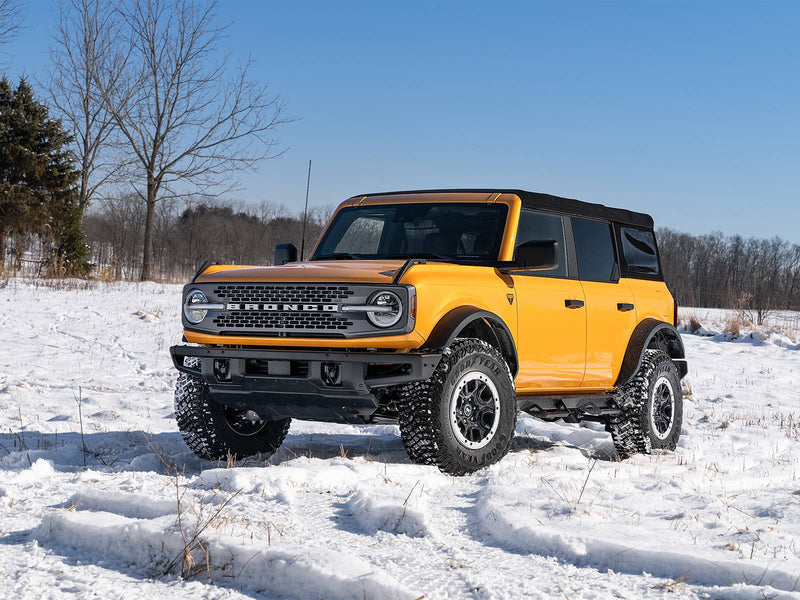 N-Fab Predator Pro nerf steps in textured black, installed along the rocker in snow, on a Ford Bronco 4-door
