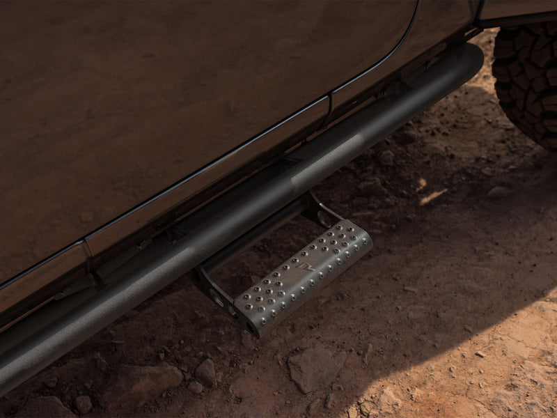 N-Fab RKR Step System in textured black, installed along the rocker on a dirt trail