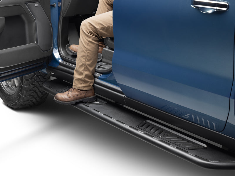 N-Fab Roan running boards in textured black, boot on the step at an open door, on a GMC Sierra 1500