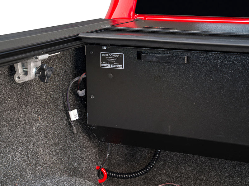 Pace Edwards BedLocker: black BedLocker canister at the front of the bed with its label and power wiring, carpet liner