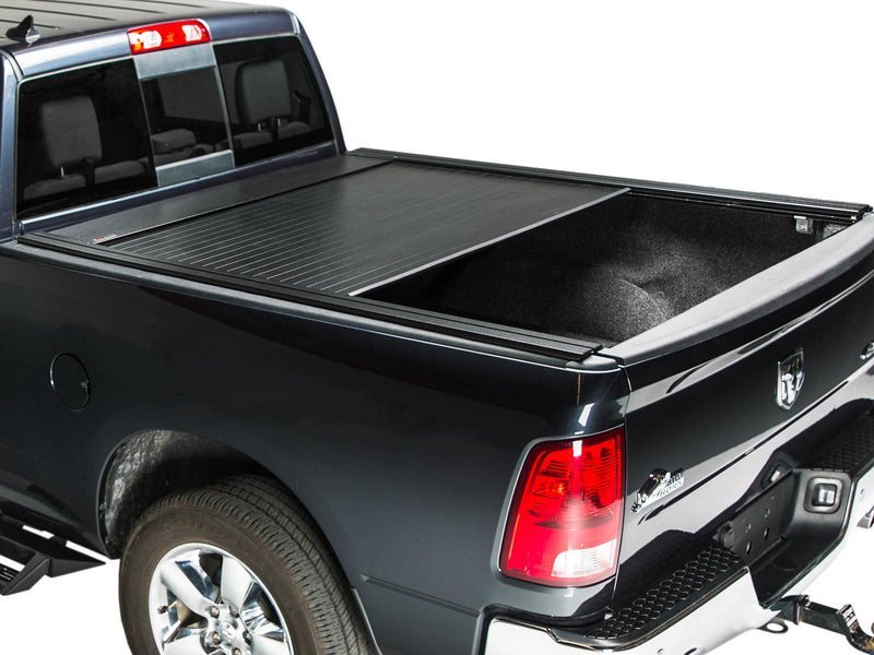 Pace Edwards BedLocker: black retractable cover about half open on a black pickup bed, rear three-quarter studio view