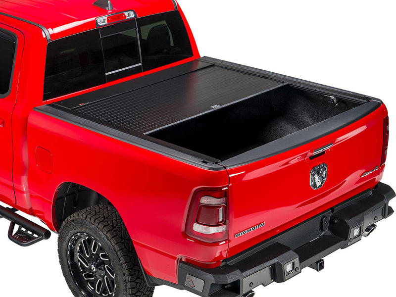 Pace Edwards BedLocker: black retractable cover about half retracted on a red pickup bed, studio rear three-quarter view