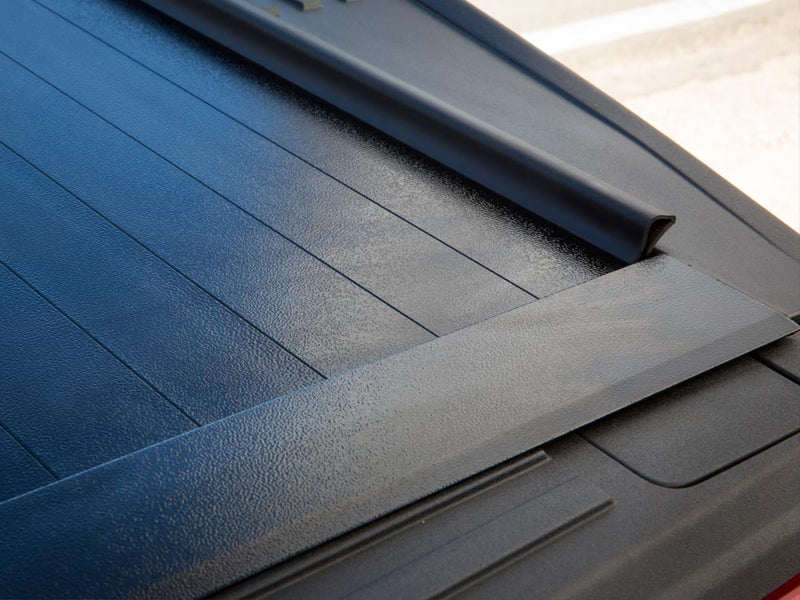 Pace Edwards BedLocker: close-up of black aluminum slatted tonneau cover surface meeting the front canister seal