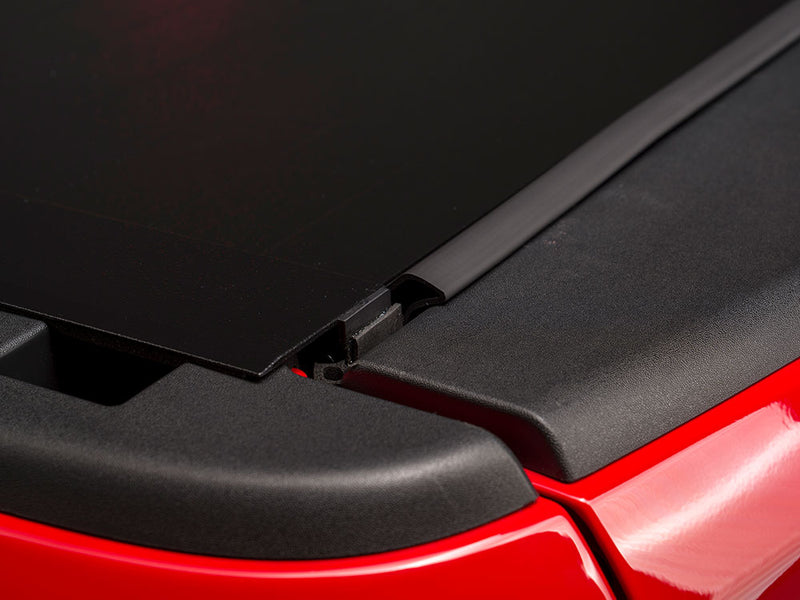 Pace Edwards BedLocker: close-up of the closed black cover edge meeting the rail end cap on a red bed rail