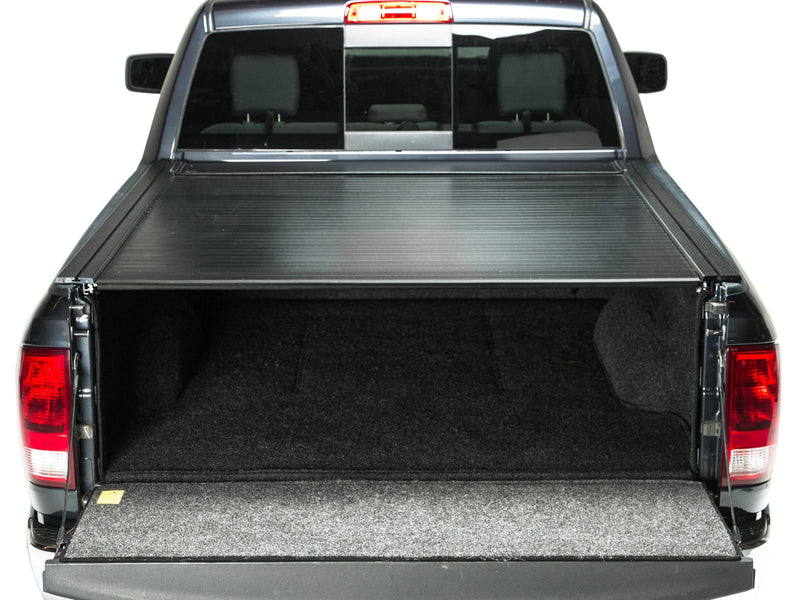 Pace Edwards BedLocker: rear view of a black pickup bed with the retractable cover closed and tailgate down showing a carpeted bed