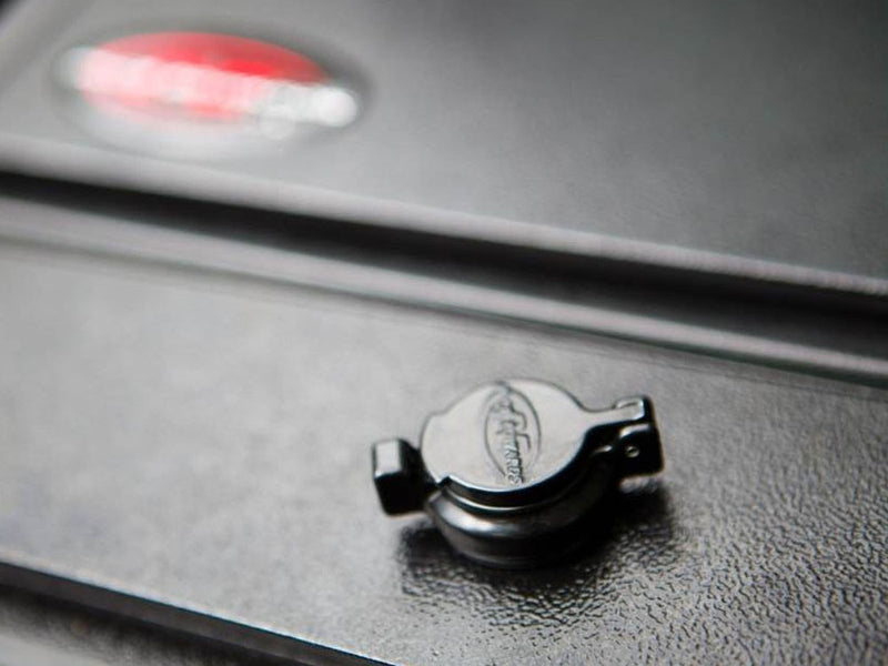 Pace Edwards Full Metal JackRabbit: close-up of a black lock cap on dark metal slats with a blurred red emblem behind
