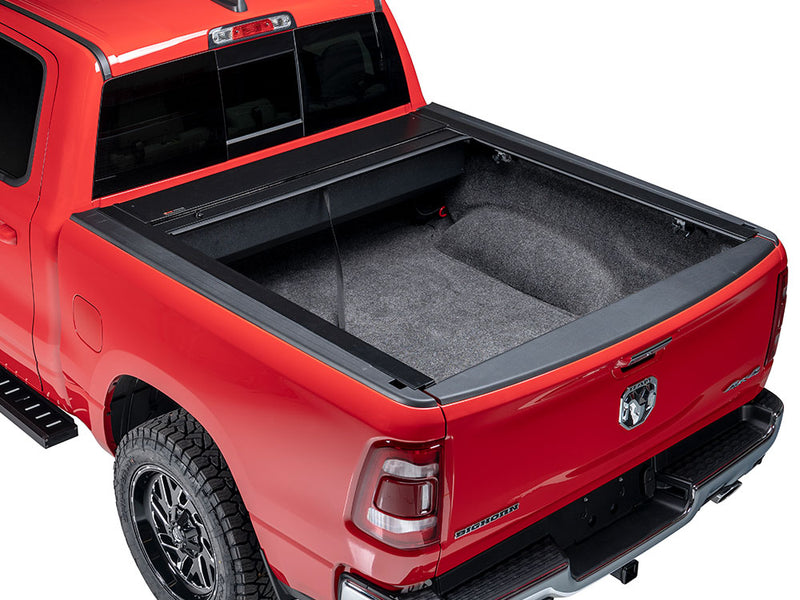 Pace Edwards Full Metal JackRabbit: retractable cover fully open on a red pickup, canister at the front of a carpet-lined bed