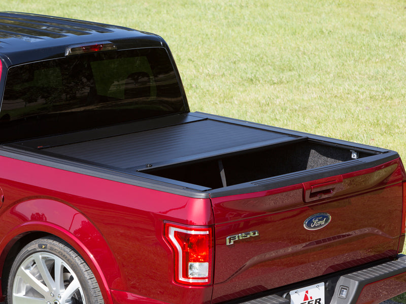 Pace Edwards JackRabbit: black retractable cover rolled about halfway open on a red pickup bed