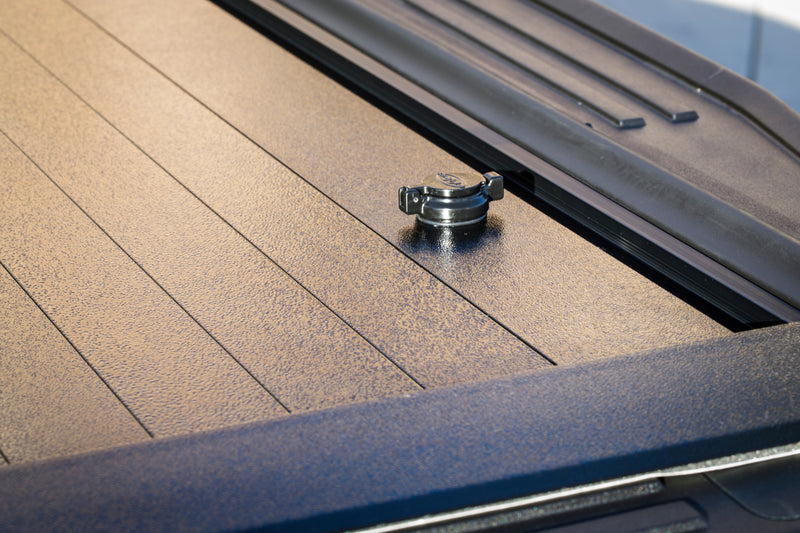 Pace Edwards JackRabbit: close view of the tailgate-end lock on closed textured vinyl cover slats