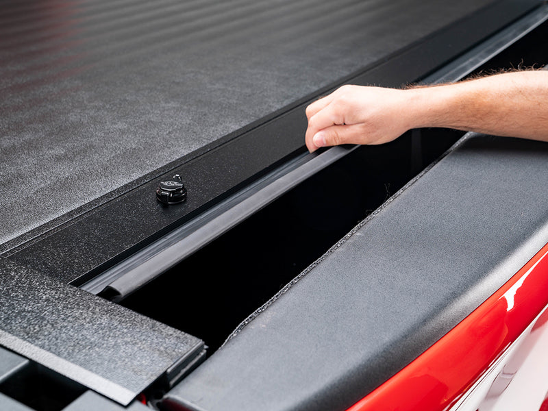 Pace Edwards JackRabbit: hand pulls the textured black cover's end slat along the rail, bed partly exposed