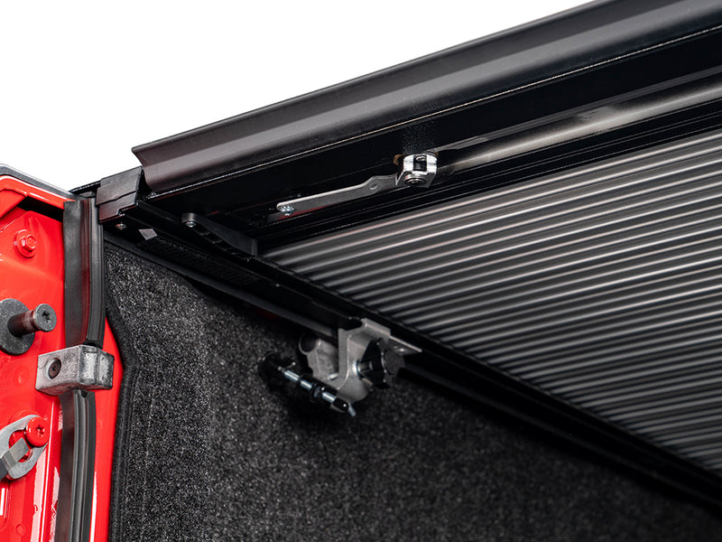 Pace Edwards JackRabbit: rail clamp and black side rail along a red bed wall, carpeted bed liner below
