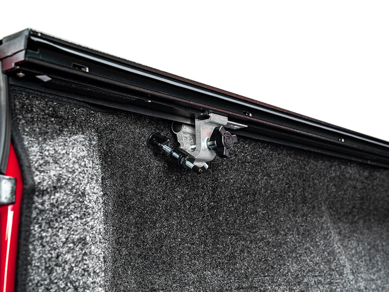 Pace Edwards JackRabbit: rail clamp securing the black side rail to the bed wall above a carpeted bed liner
