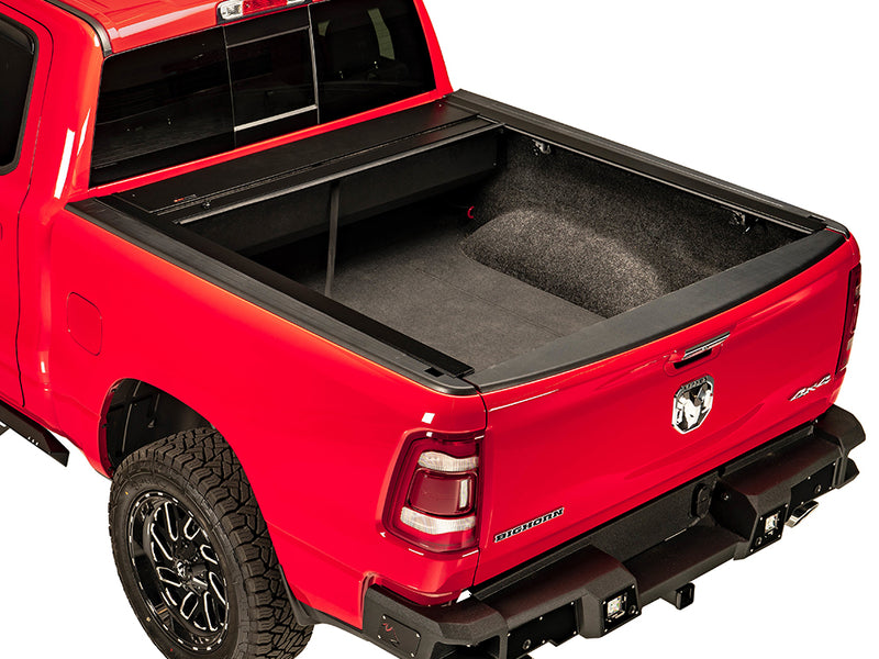 Pace Edwards JackRabbit: retractable cover fully rolled into its canister on a red pickup, carpeted bed exposed, white background