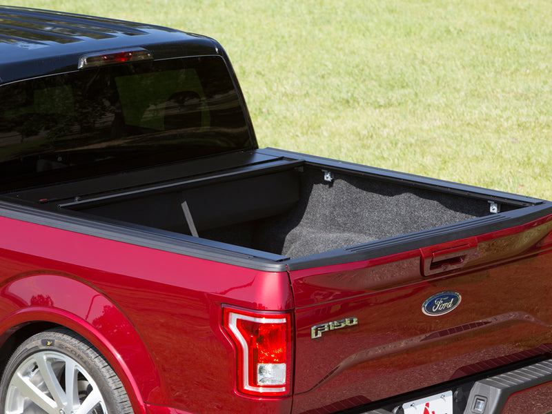 Pace Edwards JackRabbit: retractable cover fully rolled into its front canister on a red pickup, carpeted bed exposed