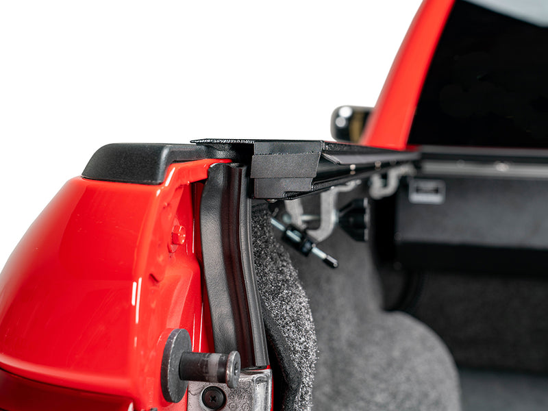 Pace Edwards JackRabbit: tailgate end of the black side rail and clamp on a red truck bed, carpeted liner inside