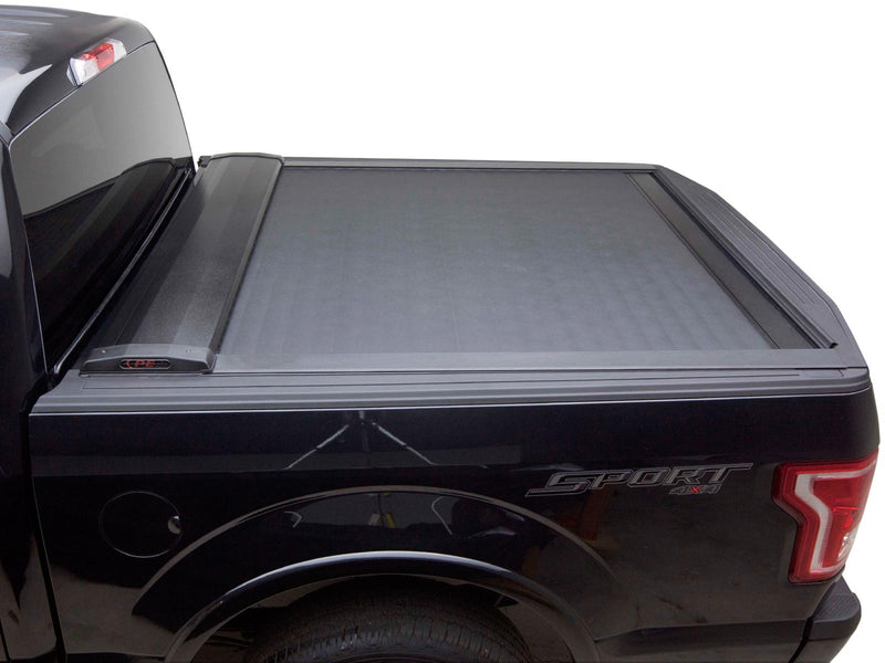 Pace Edwards SwitchBlade: black retractable tonneau cover fully closed on a black pickup bed, side view on white background