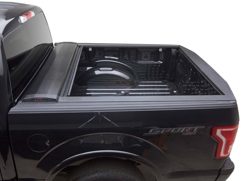 Pace Edwards SwitchBlade: retractable cover fully rolled into its front canister on a black pickup, open bed visible, side view