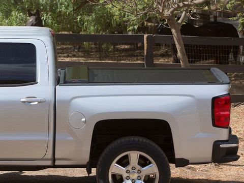 Pace Edwards SwitchBlade: side view of a silver pickup bed with a black retractable tonneau cover closed, horses behind a fence