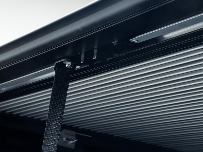 Pace Edwards SwitchBlade: underside of closed aluminum cover slats with the black pull strap hanging near the tailgate end