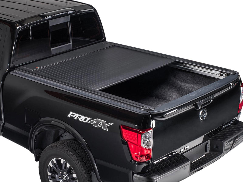 Pace Edwards UltraGroove Electric: matte black retractable cover about half retracted on a black pickup bed, studio rear three-quarter view