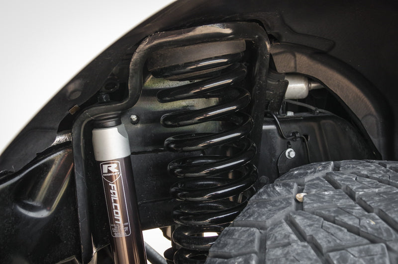 ReadyLIFT Coil Spring Lift Kit on a vehicle: black coil spring and Falcon shock with ReadyLIFT R badge installed in a front wheel well