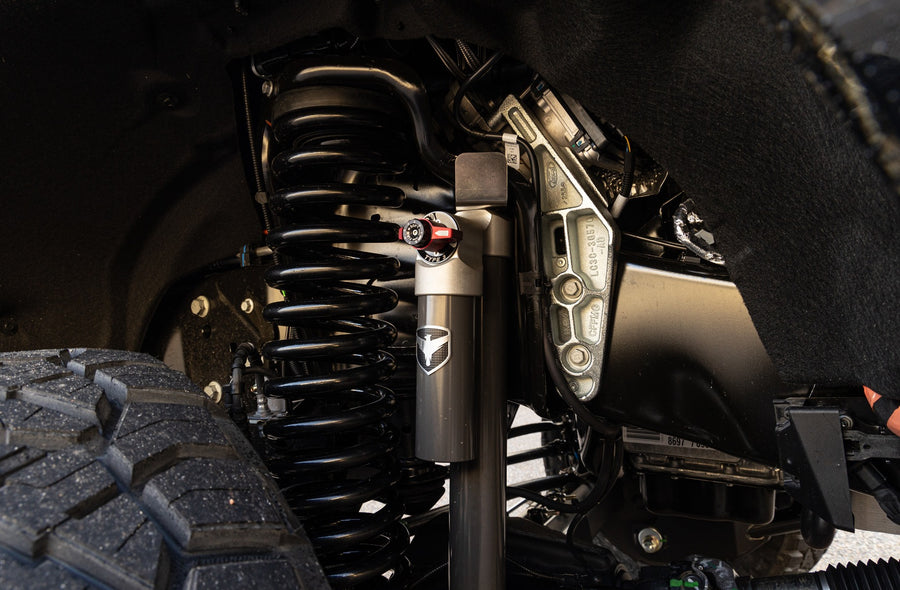 ReadyLIFT Coil Spring Suspension System on a vehicle: black coil spring and Falcon shock installed behind a front tire in a Super Duty wheel well