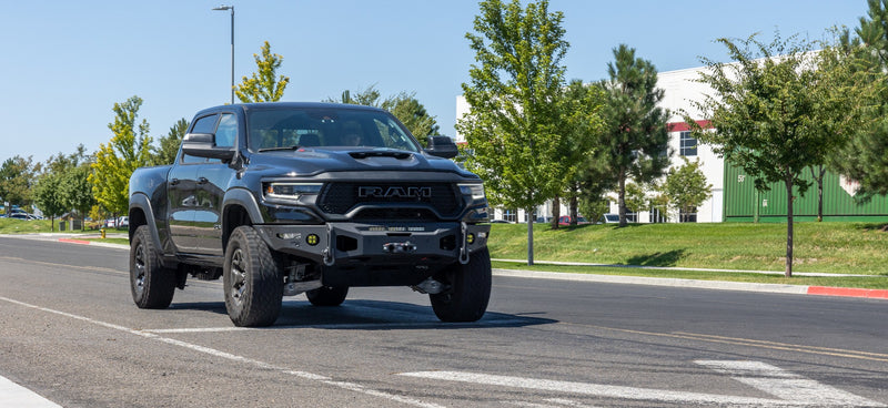 ReadyLIFT Leveling Kit installed on a Ram 1500 TRX: black Ram 1500 TRX crew cab on a suburban street with trees behind