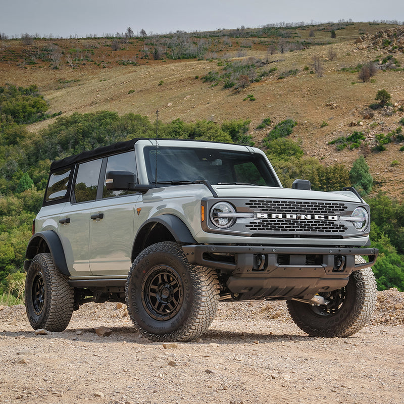 ReadyLIFT Leveling Kit installed on a Ford Bronco: gray Ford Bronco four-door leveled on black wheels and all-terrain tires on a dirt hillside