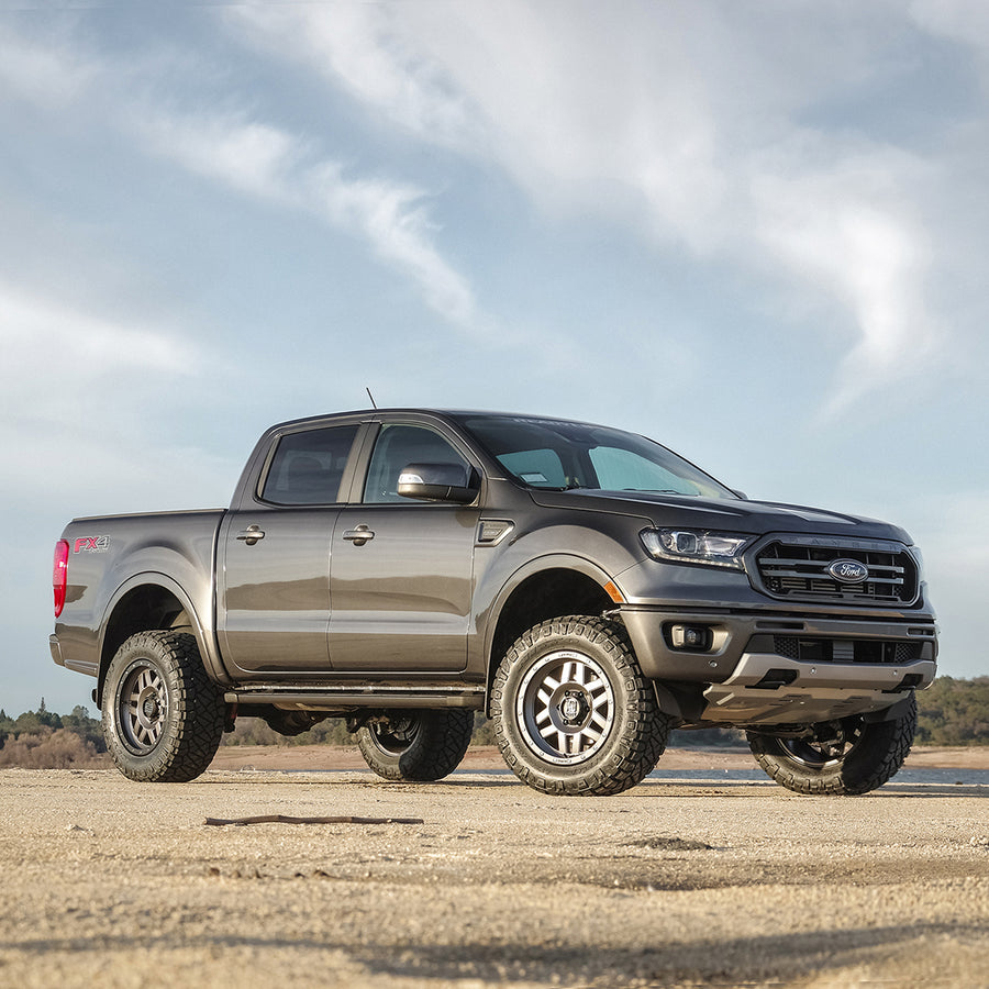 ReadyLIFT Leveling Kit installed on a Ford Ranger: gray Ford Ranger crew cab leveled on bronze wheels on a sandy flat under cloudy sky