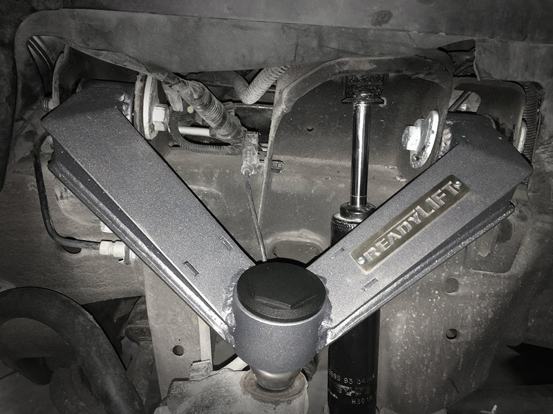 ReadyLIFT Leveling Kit on a vehicle: gray ReadyLIFT fabricated upper control arm installed in a GM front suspension seen from the wheel well