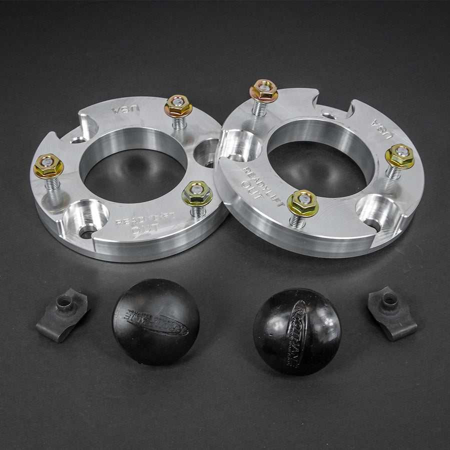 ReadyLIFT Leveling Kit, full kit on a studio background: two aluminum strut spacers with studs, two black bump stops and clips on a dark gray background