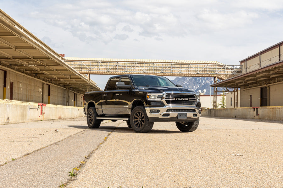 ReadyLIFT Lift Kit installed on a Ram 1500: A black lifted Ram 1500 Crew Cab parked between two loading docks