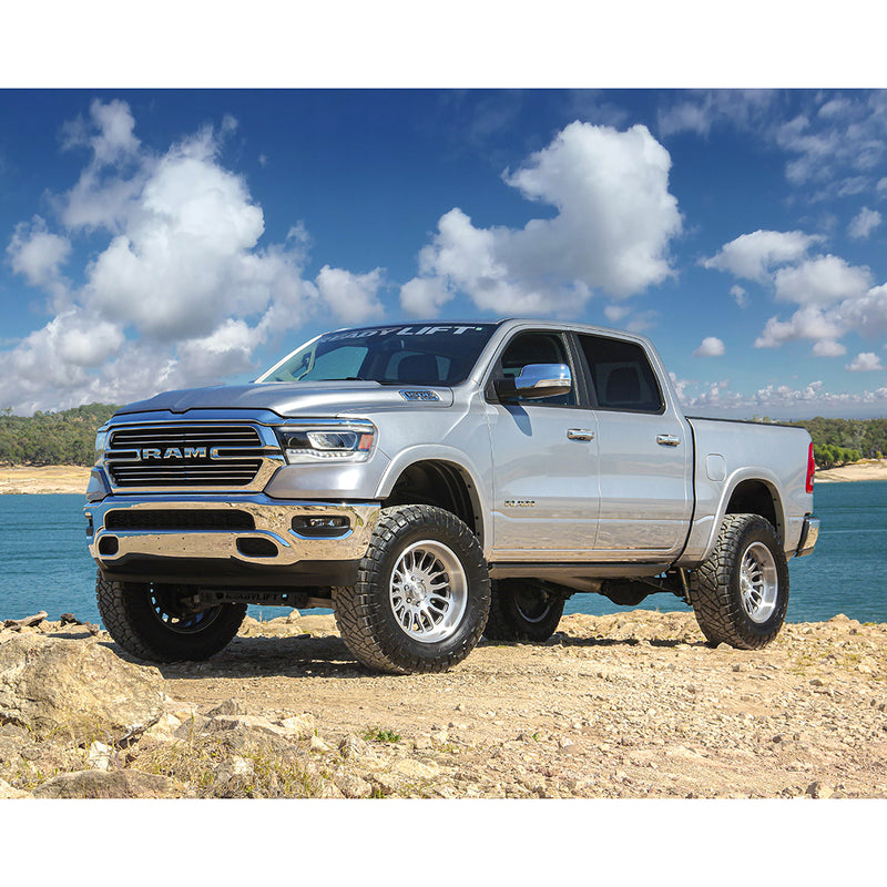 ReadyLIFT Lift Kit installed on a Ram 1500: silver Ram 1500 crew cab lifted on large all-terrain tires beside a lake, ReadyLIFT banner on the windshield