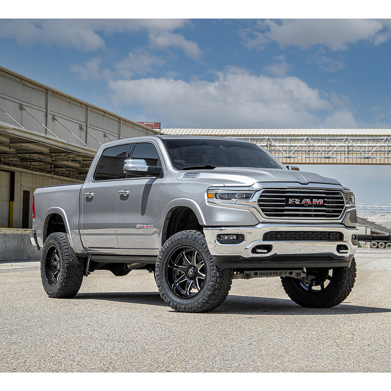 ReadyLIFT Lift Kit installed on a Ram 1500 Limited: silver Ram 1500 Limited crew cab lifted on black wheels and mud tires at an industrial yard